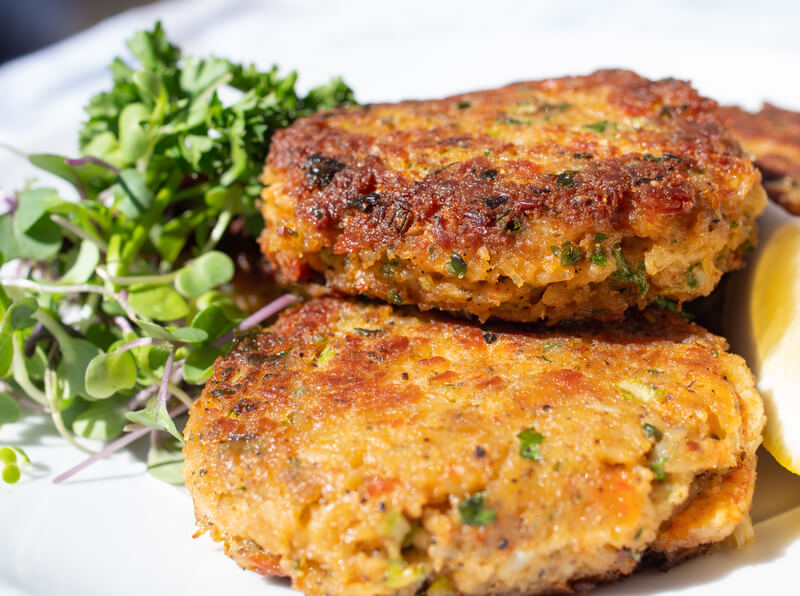 Savoury, crisp and starchy, fishcakes, crab cakes.. Fried fish patties served on a plate with salad on the side.
