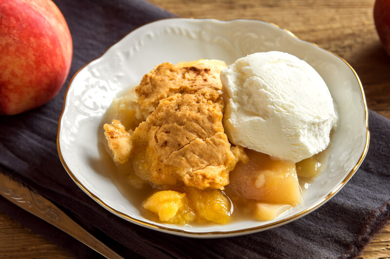Peach cobbler with ice cream. Homemade peach cobbler with vanilla ice cream over rustic wooden background - healthy pastry dessert