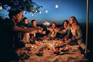 A group of friends sharing a celebratory moment at an outdoor evening picnic.