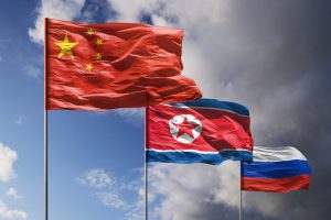 Flags of China, North Korea and Russia above dark sky