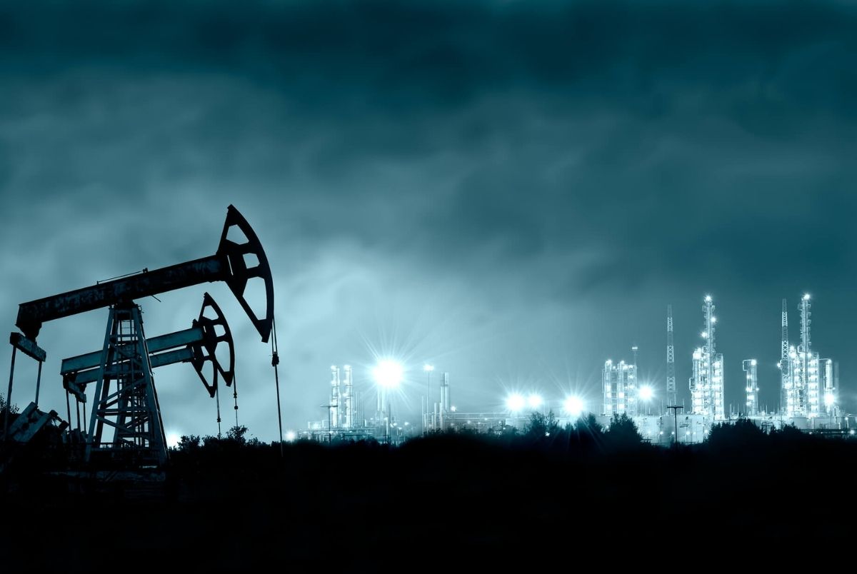 Pump jack and grangemouth refinery at night. Group oil rigs and brightly lit industrial site at night. Toned.