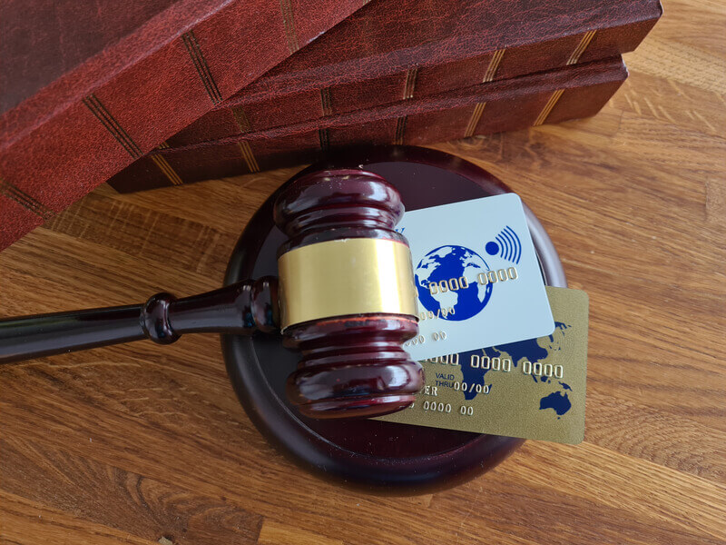 Judge gavel with legal texts and credit cards, symbolizing the intersection of law and finance in the courtroom concept