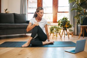 Fitness yoga, laptop and senior woman in video call class for workout, wellness motivation and pilates exercise in home living room. Healthy person in cardio with pc technology for support tutorial.