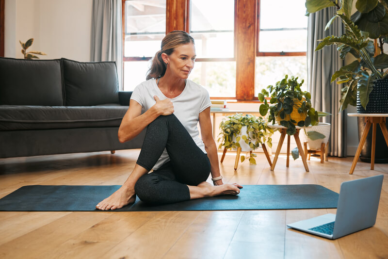 Fitness yoga, laptop and senior woman in video call class for workout, wellness motivation and pilates exercise in home living room. Healthy person in cardio with pc technology for support tutorial.