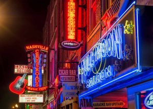 The vibrant neon-lit facades of famous honky-tonks on Lower Broadway in Nashville, Tennessee.