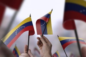 Venezuela flags in their hands on a blurred urban background. The photo illustration was created without the use of artificial intelligence, only using Photoshop.