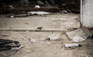 Old abandoned house and used plastic syringes. The problem of drug addiction in society. Drug addiction as a social problem. Used plastic syringes and needles on the floor of an old abandoned house