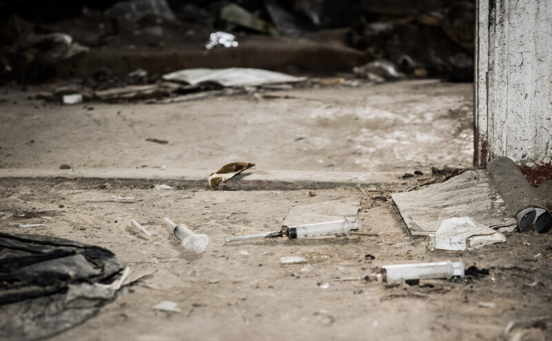 Old abandoned house and used plastic syringes. The problem of drug addiction in society. Drug addiction as a social problem. Used plastic syringes and needles on the floor of an old abandoned house