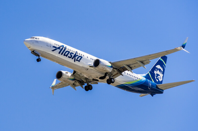 Alaska Airlines aircraft flying approaching Norman Y. Mineta San Jose International Airport and preparing for landing; blue sky background