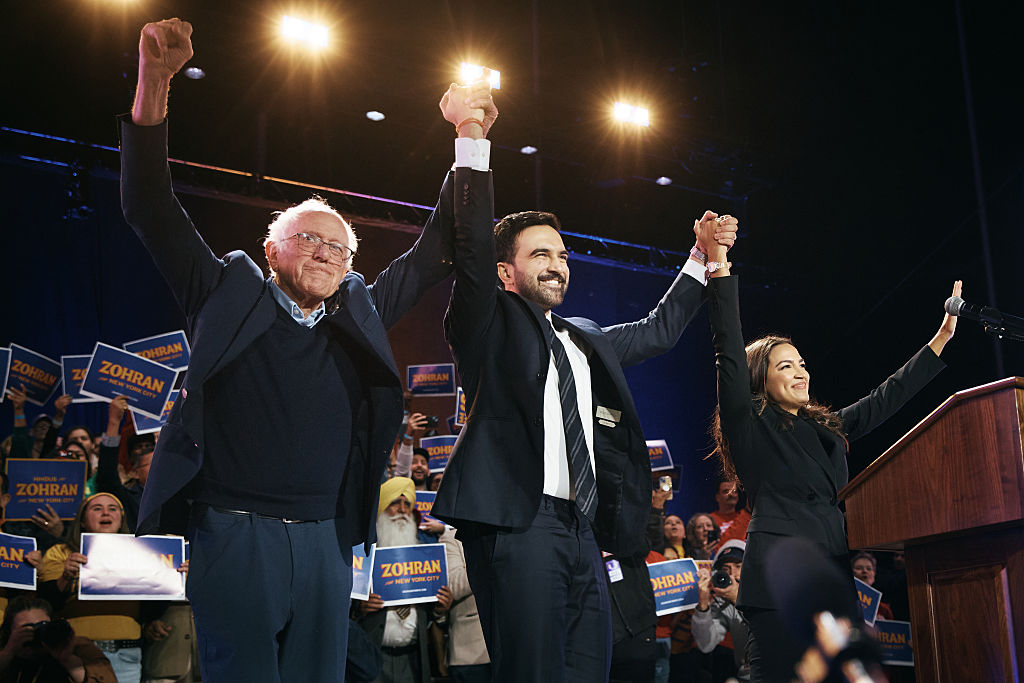 NEW YORK, NEW YORK - OCTOBER 26: New York Mayoral Candidate Zohran Mamdani, center, celebrates with Sen. Bernie Sanders (I-VT), left, and U.S. Rep. Alexandria Ocasio-Cortez (D-NY), right, during an election rally on October 26, 2025 at Forest Hills Stadium in the Queens borough of New York City. The mayoral election will take place on November 4, 2025. (Photo by Andres Kudacki/Getty Images)