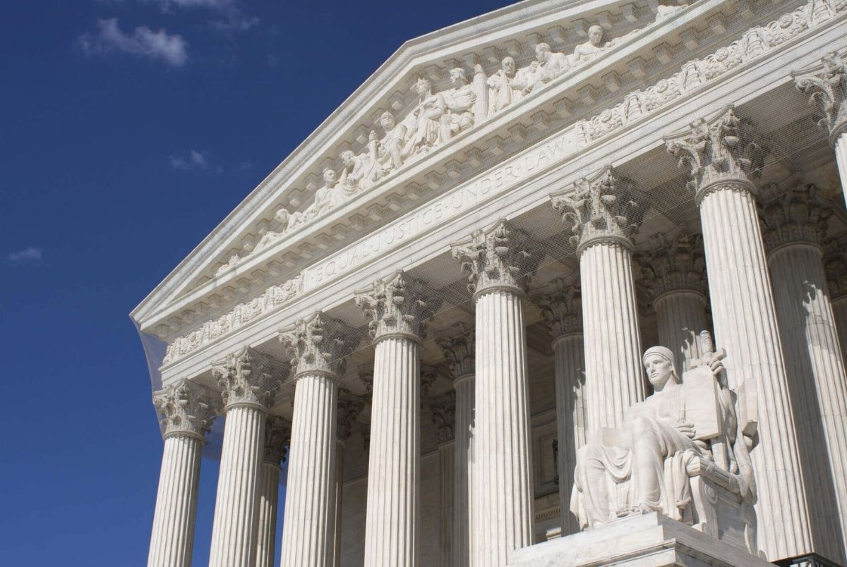 A landscape photo of the US Supreme Court with blue skies in summer