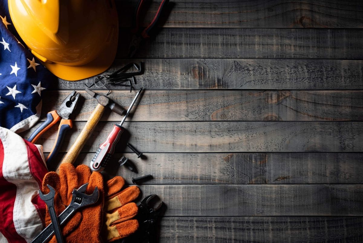 Happy Labor day concept. American flag with different construction tools on dark wooden background, with copy space for text.