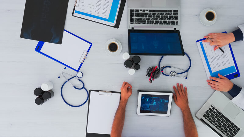 Top view of physicians in meeting with reports and laptop in medical clinic analysing x-ray discussing. Team doctors working in clinic on copy space, flat lay using modern technology.