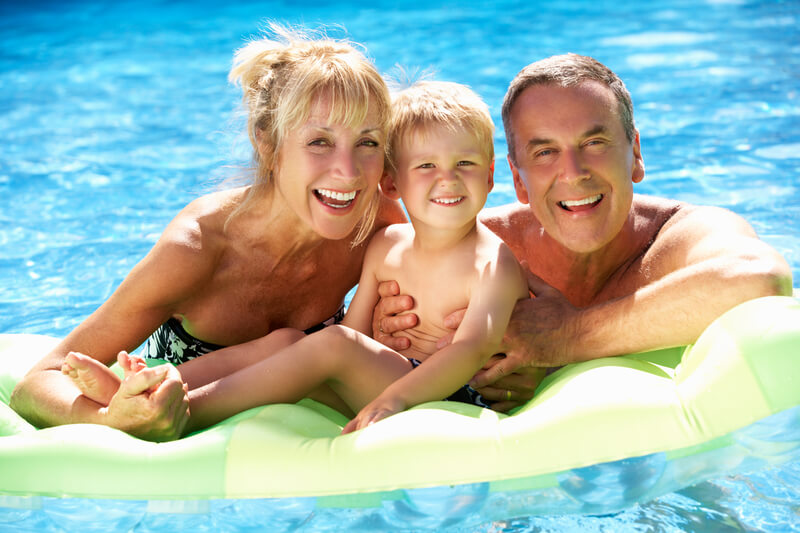 Grandparents And Grandson In Swimming Pool. Grandparents And Grandson Having Fun In Swimming Pool During Summer