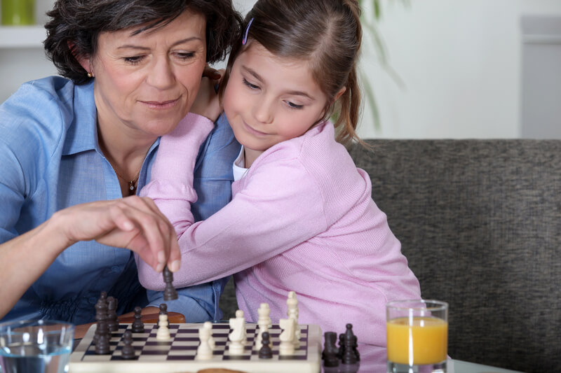 Grandmother playing chess with little girl