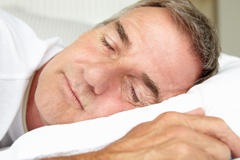 Head and shoulders mid age man sleeping in bed